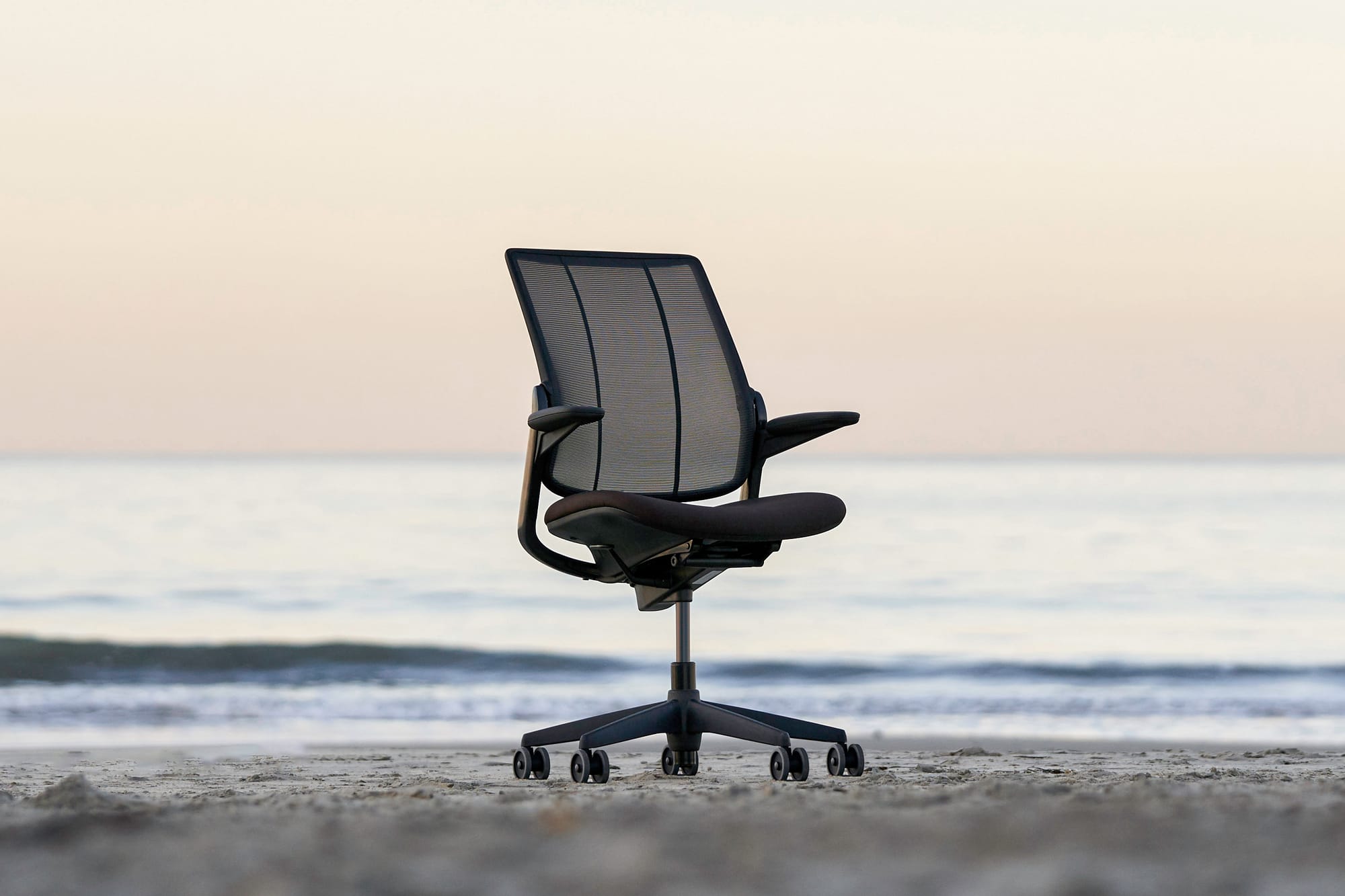 Photo of desk chair on the beach in front of a calm ocean