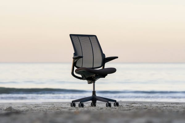 Photo of desk chair on the beach in front of a calm ocean